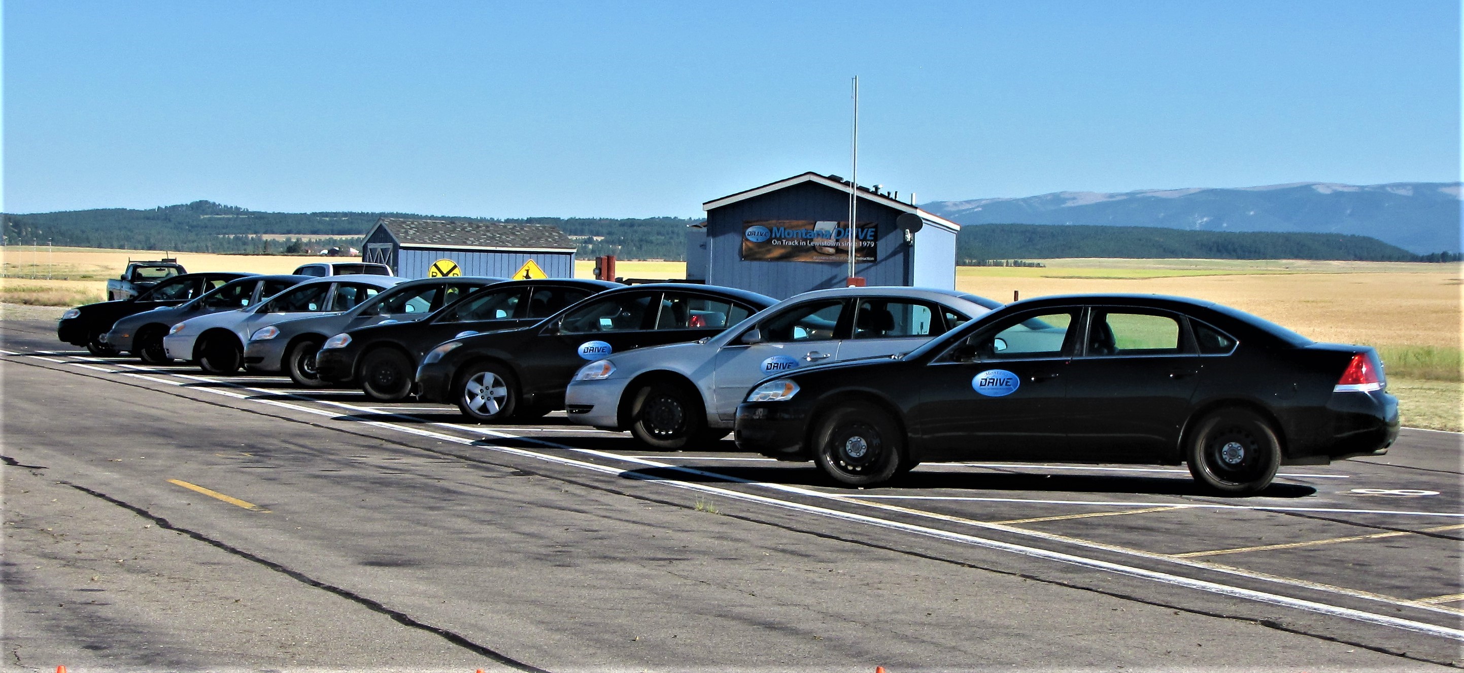 Cars lined up in a parking lot along a road